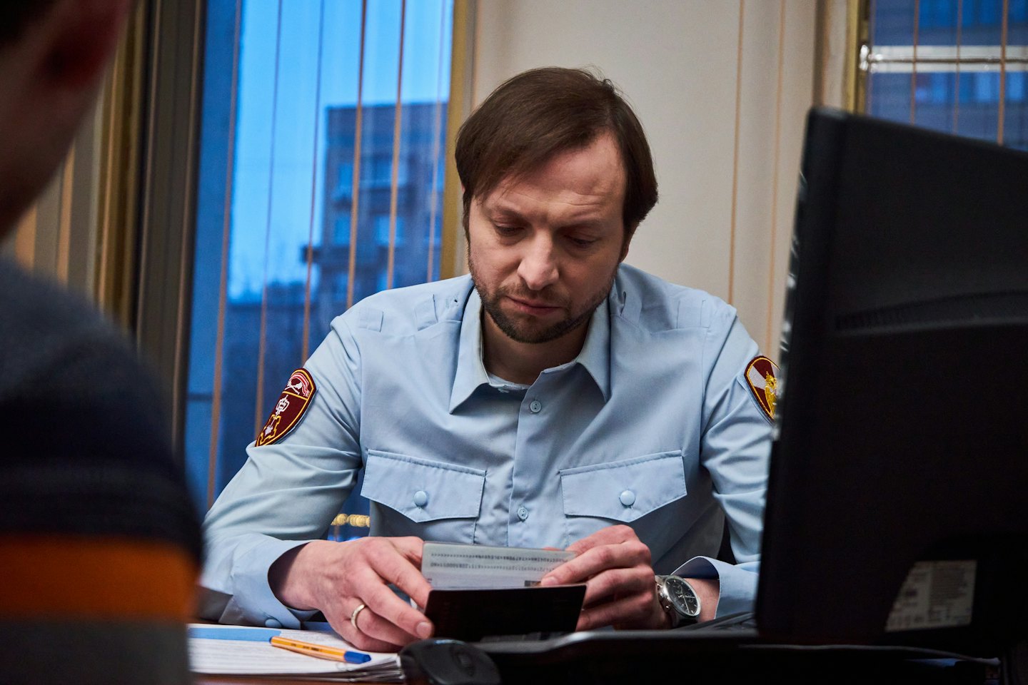 An officer examines a document at a desk in an office.