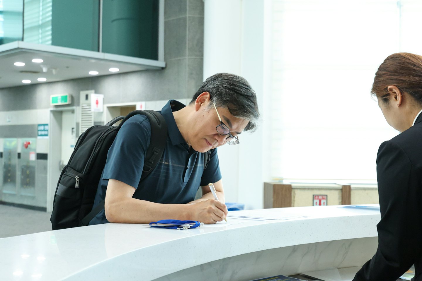 Man filling out a form at a modern reception desk.